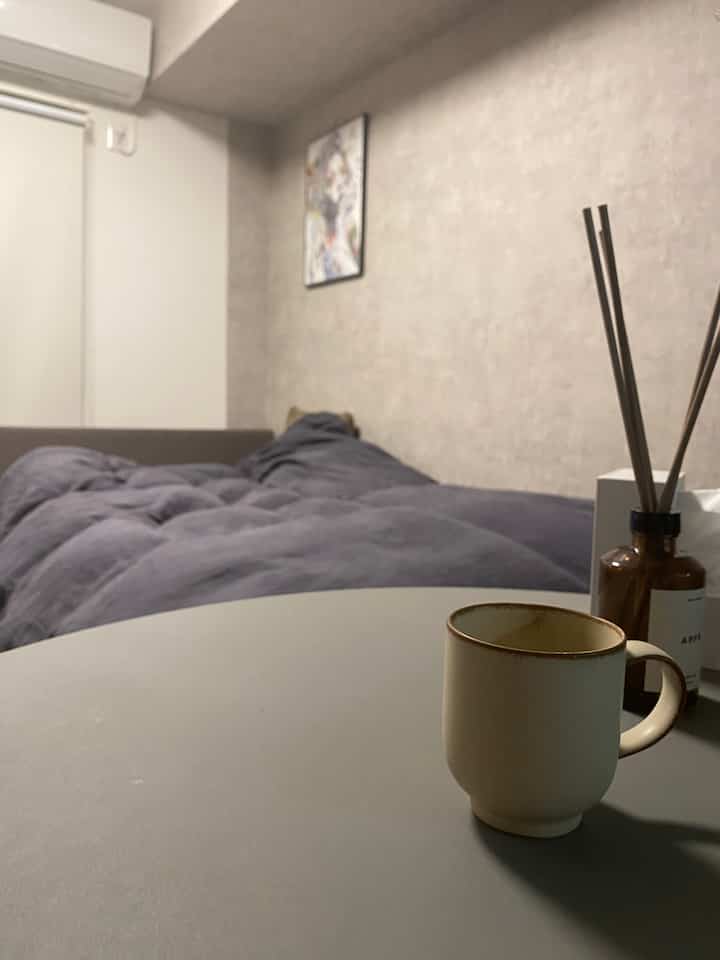 グレーの寝具とベージュの小物が配置された落ち着いた寝室、シンプルで自然な雰囲気のあるインテリア
