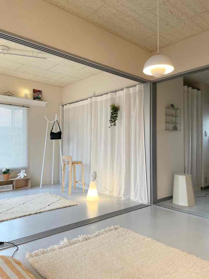 白を基調とした広々とした空間にスツールとフロアランプが配置されたシンプルなインテリア