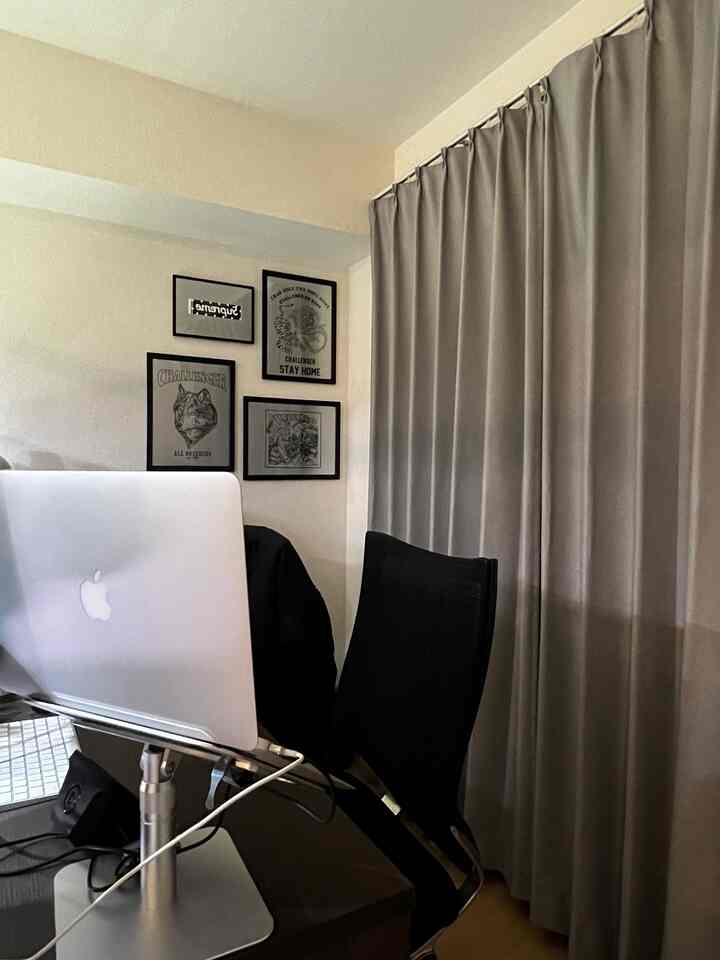 モノトーンのホームオフィス、黒のオフィスチェアとMacBookが配置された整ったデスク環境