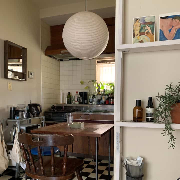 ナチュラルな色調のキッチンダイニング、木製ダイニングテーブルとヴィンテージ家具が配置された印象的な空間