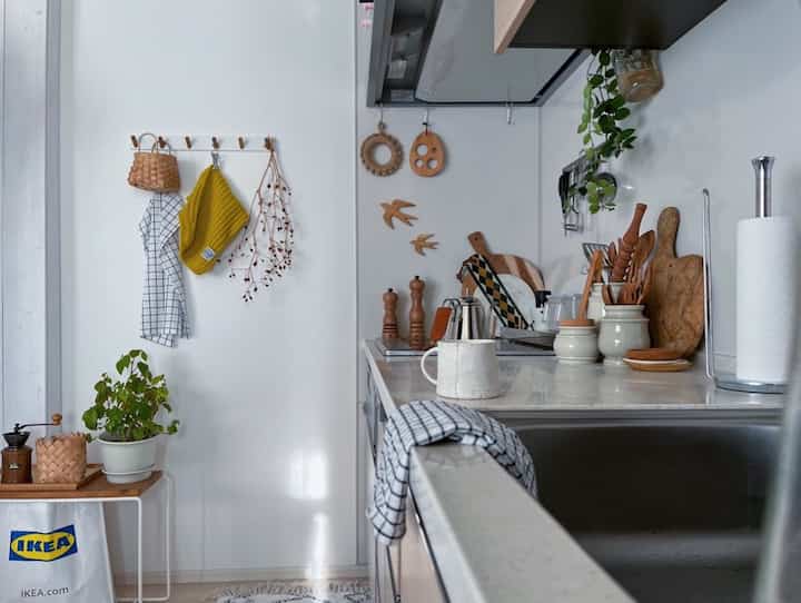 白と木目調が調和した小さなキッチン空間、カフェ風のインテリアで様々なキッチン用品と調理器具が整然と配置されている