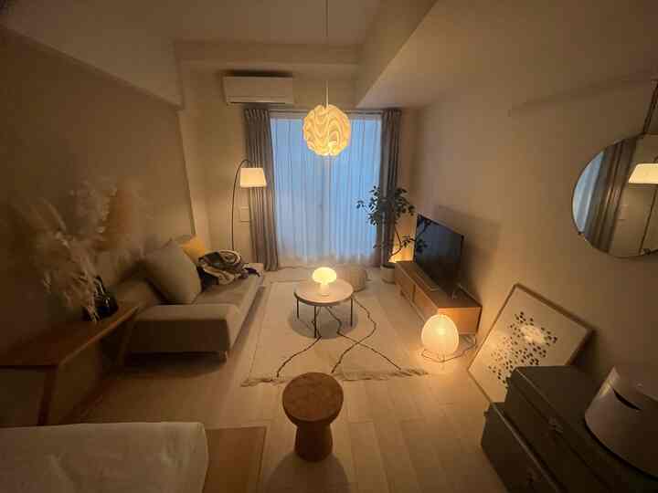 温かみのある木目調と白を基調としたリビング、快適なソファと照明が配置された雰囲気のあるインテリア