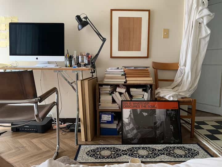 ナチュラルな木目調と白い壁のホームオフィス、机と椅子、本棚が配置された落ち着いた書斎のインテリア