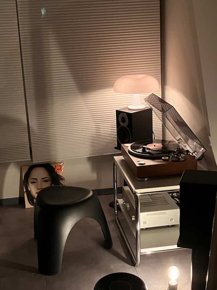 Cozy living room in warm white and black tones featuring a record player and a stool for music enjoyment