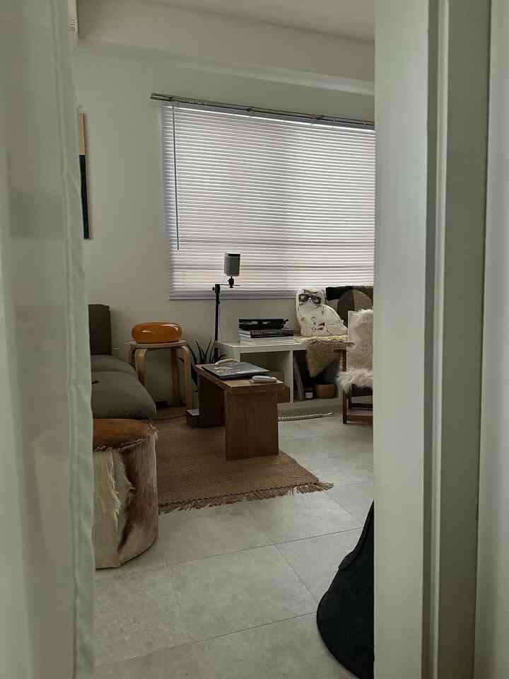 Natural-toned single household living room featuring wooden bench, sofa, and jute rug creating cozy atmosphere