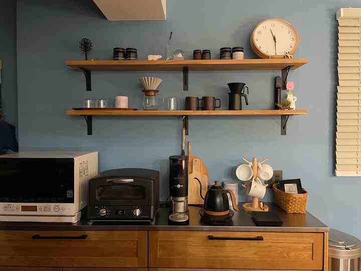 青い壁と木製の棚が配置されたキッチン空間、コーヒー器具が置かれた雰囲気のあるおうちカフェ風インテリア