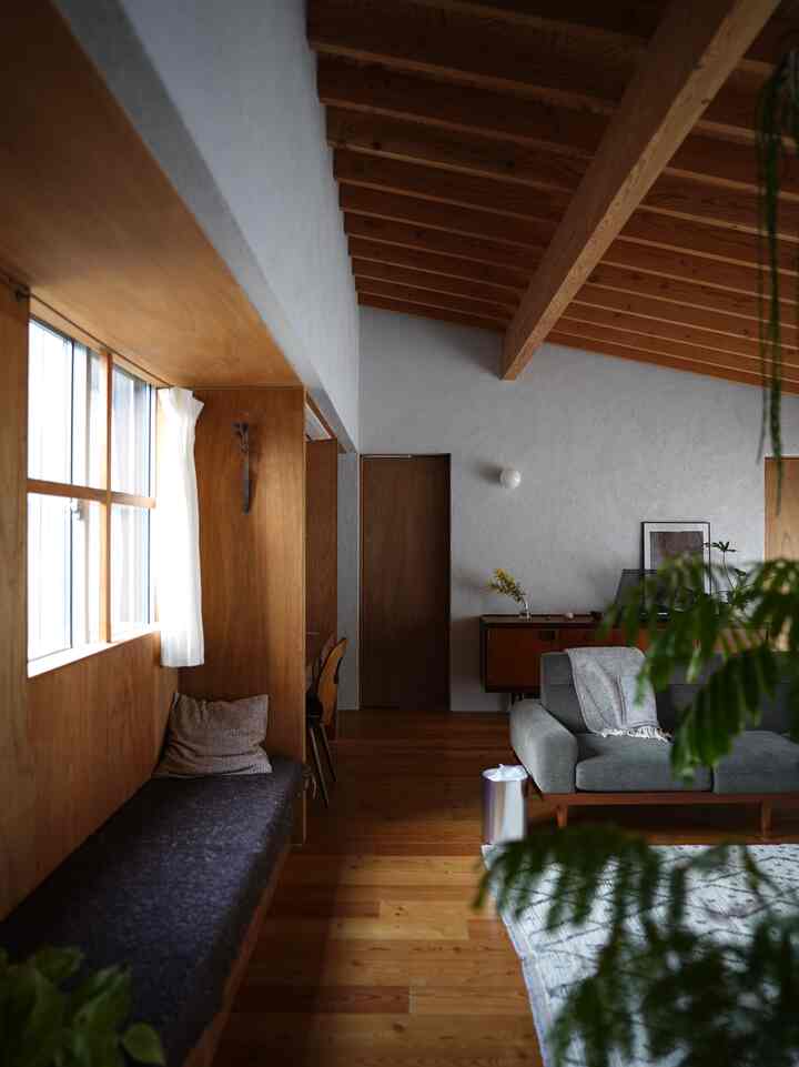 Warm and cozy living room with natural wood tones and a gray sofa under exposed wooden ceiling beams