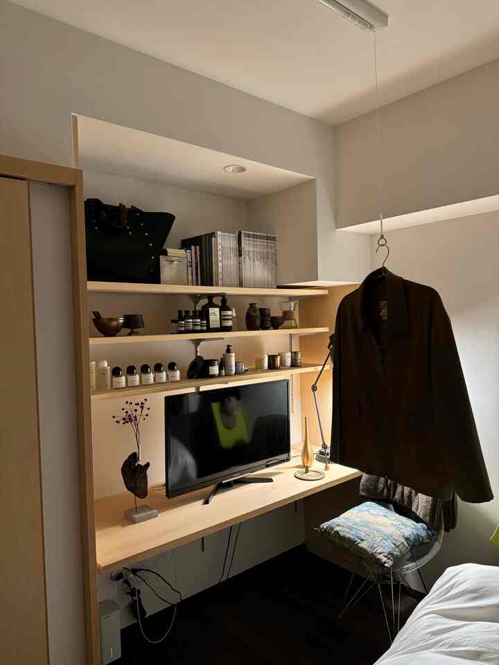 白い壁と木目調の机、棚が配置されたモダンな狭いホームオフィスのインテリア