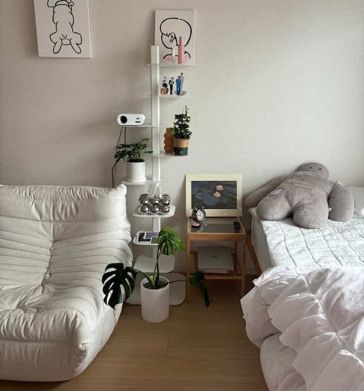 白と木目調の調和がとれた寝室、ソファとナイトテーブルが配置された落ち着きのあるインテリア