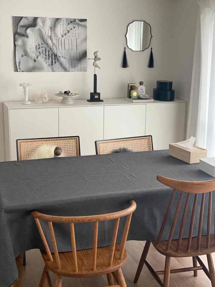 Natural and simple dining room with white walls, wood tone chairs, a charcoal dining table, and curtains