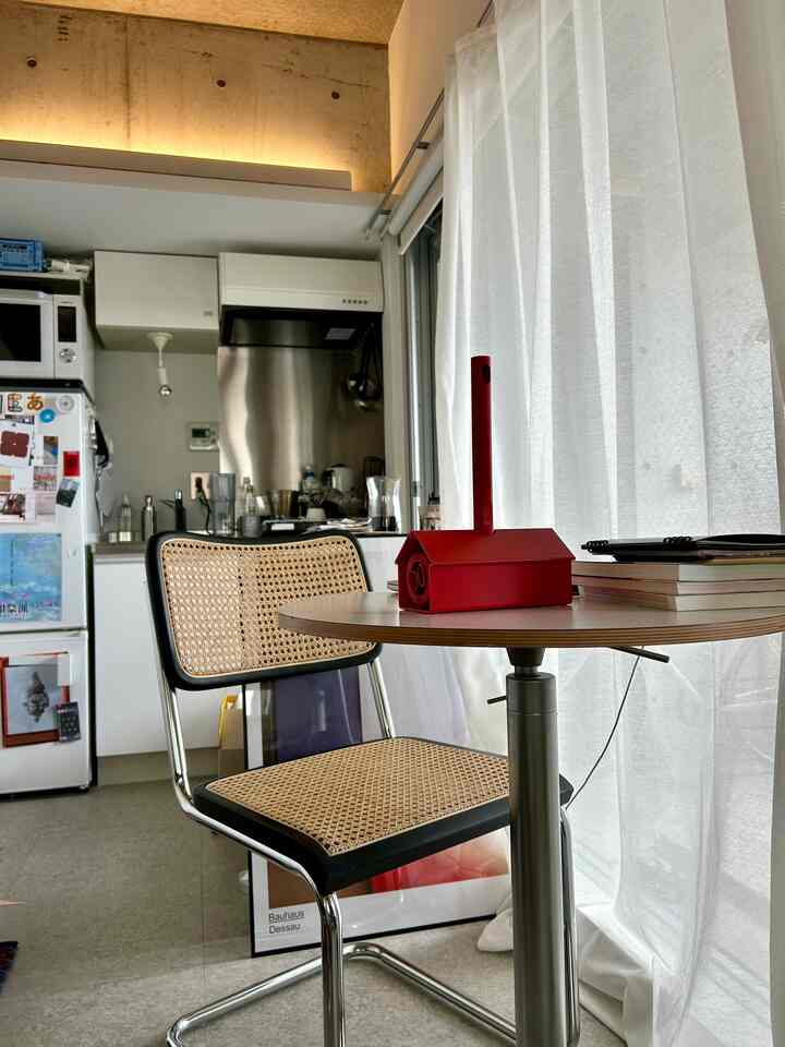 明るい白いカーテンとナチュラルなラタンチェアが配置されたワンルームのダイニングスペース