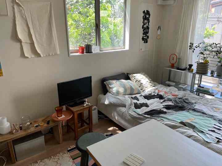 ホワイトと木目調の寝室、ベッドとデスクが配置され、自然光が差し込み雰囲気のあるインテリア