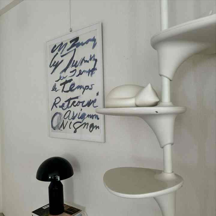 Simple indoor space in white tones featuring a white cat tower and a sleeping cat-shaped decor