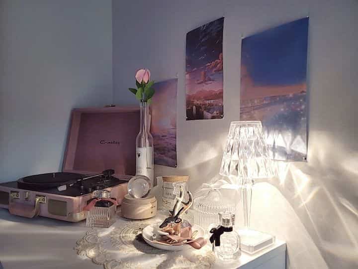 Cozy home cafe space featuring warm pink tones and a retro turntable alongside a glowing table lamp with decorative posters