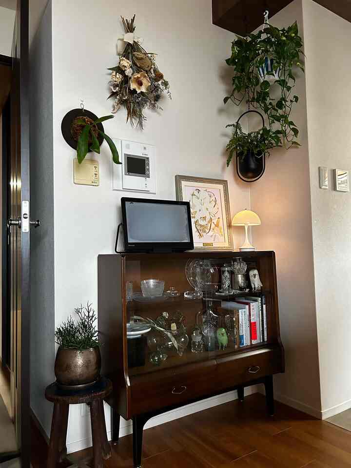 白い壁と茶色のヴィンテージコンソールにドライフラワーと観葉植物が配置された雰囲気のある空間