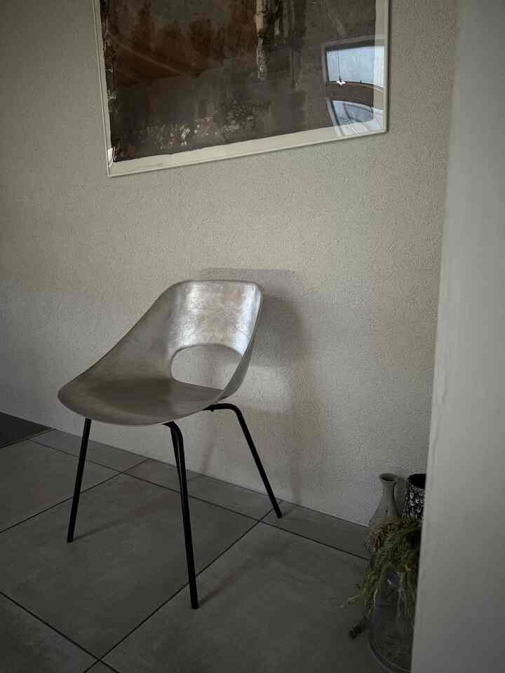 A monotone space featuring a metallic armchair centrally placed, showcasing a simple and natural color scheme interior