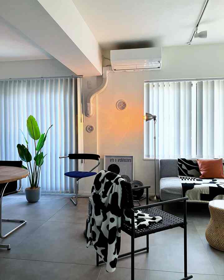 White and green toned living room featuring gray sofa, floor lamp, black chair with a natural atmosphere