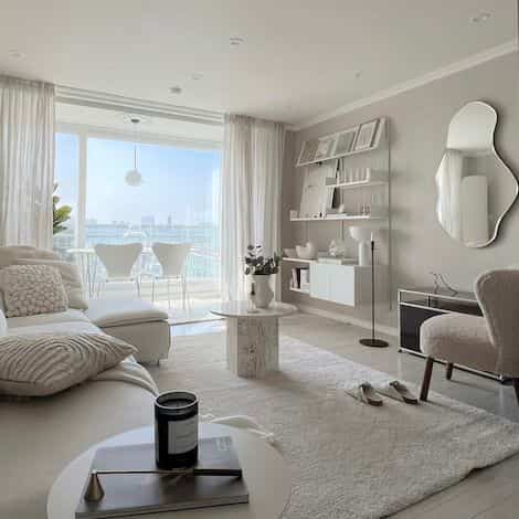Ivory and wood-toned Japandi style living room featuring a large sofa, round coffee table, and a unique wall mirror creating a serene atmosphere
