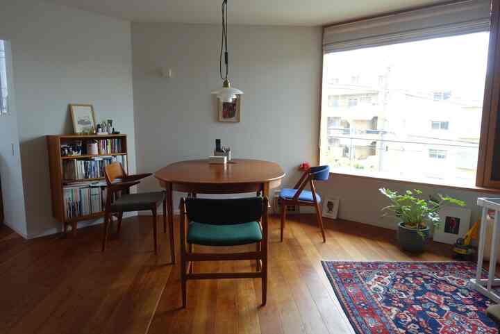 温かみのある木目調と白い壁が調和したリビングダイニング、木製のテーブルと椅子が配置され、自然な雰囲気のあるインテリア