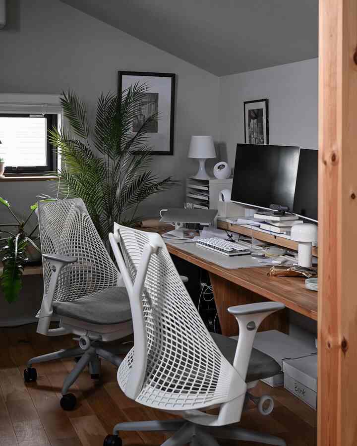 ナチュラルモダンな色調の書斎、2脚のセイルチェアと広々としたデスク、植物が配置されたすっきりとした作業空間