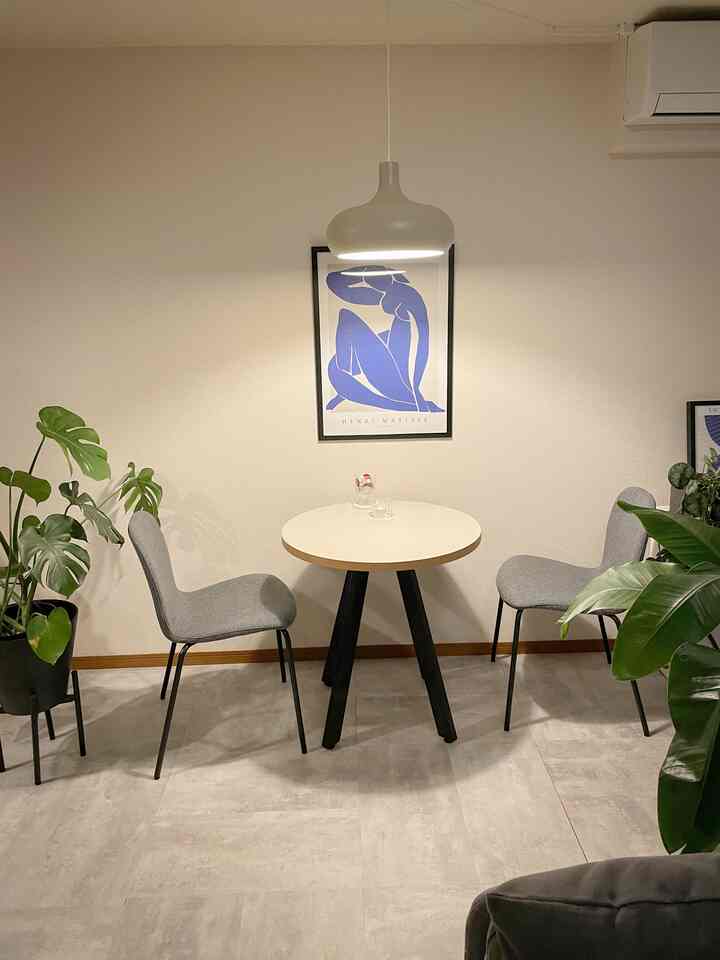 白とグレーのトーンの小さなダイニング、グレーの椅子と丸テーブル、ペンダントライトが配置されたシンプルでナチュラルな雰囲気のインテリア