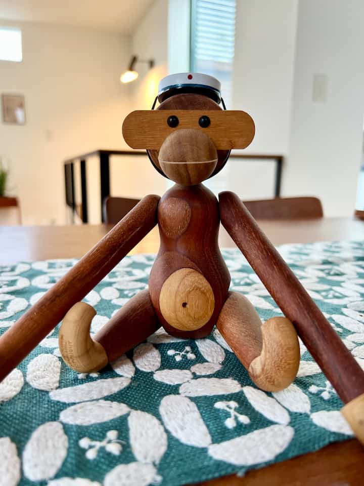 温かみのある木目調と青いテーブルランナーが調和した北欧スタイルの空間に、中央に配置された木製のサルのオブジェ