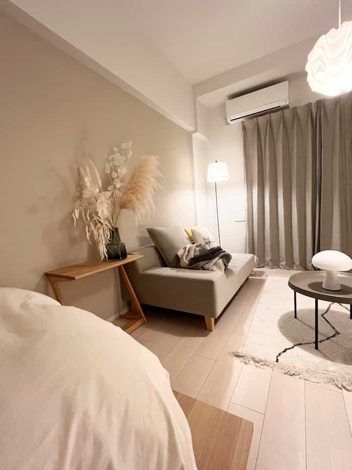 ベージュ系のリビング、グレーのソファとサイドテーブル、フロアランプが配置された自然なモダンな空間