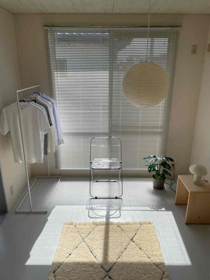 Bright white compact studio apartment featuring simple furniture and natural accents