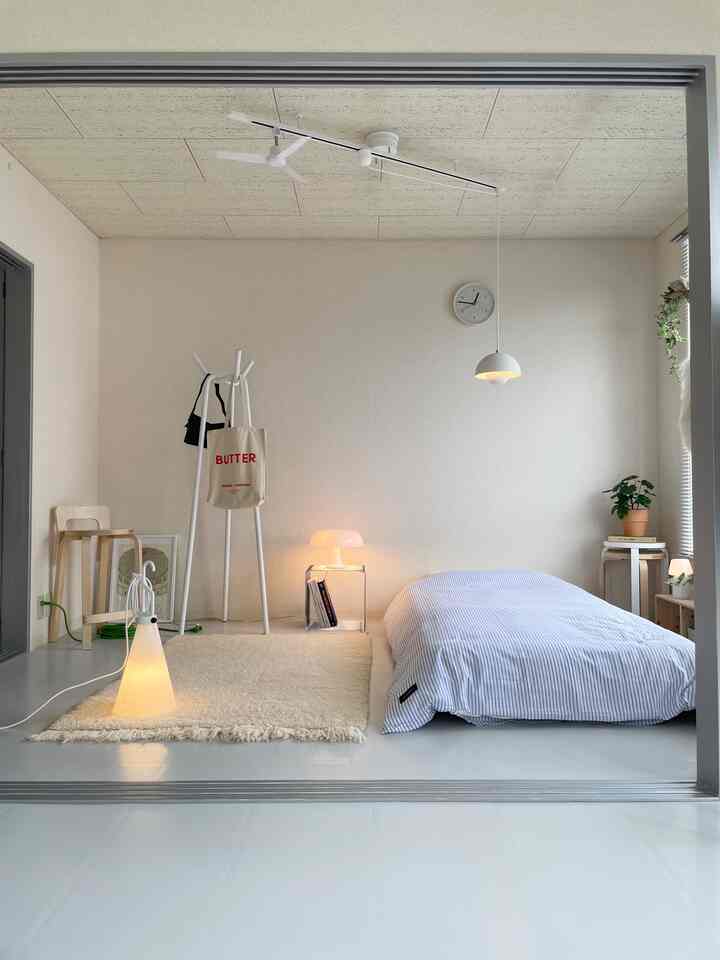Bright natural-toned bedroom featuring blue striped bedding and soft lighting in a simple cozy space