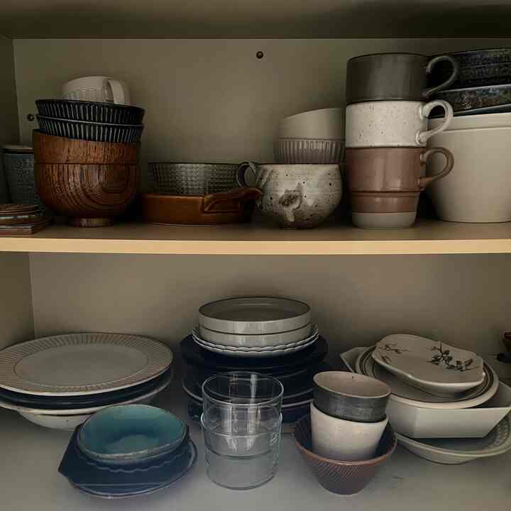 A modern kitchen shelving displaying a variety of white and brown plates and bowls neatly organized for kitchenware storage