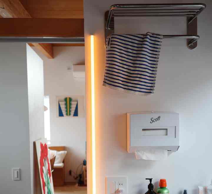 ホワイトトーンのパウダールーム、壁掛けタオルとスリムなLED照明が配置されたモダンで清潔感のある空間