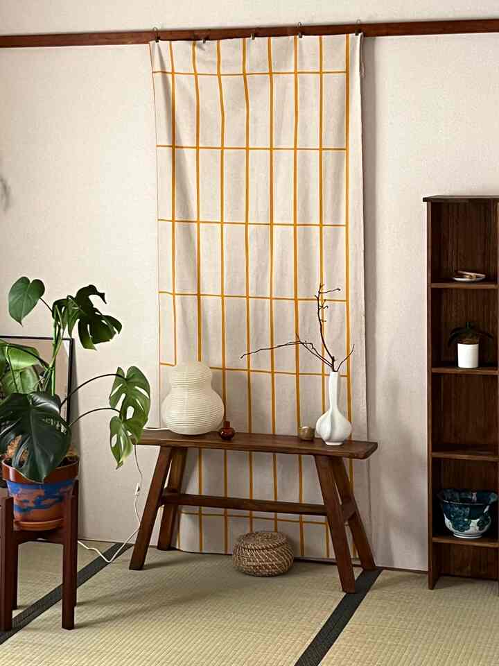 ベージュの壁と木目調の家具が配された畳の部屋、花瓶と植物が配置された自然な雰囲気のある和風リビング