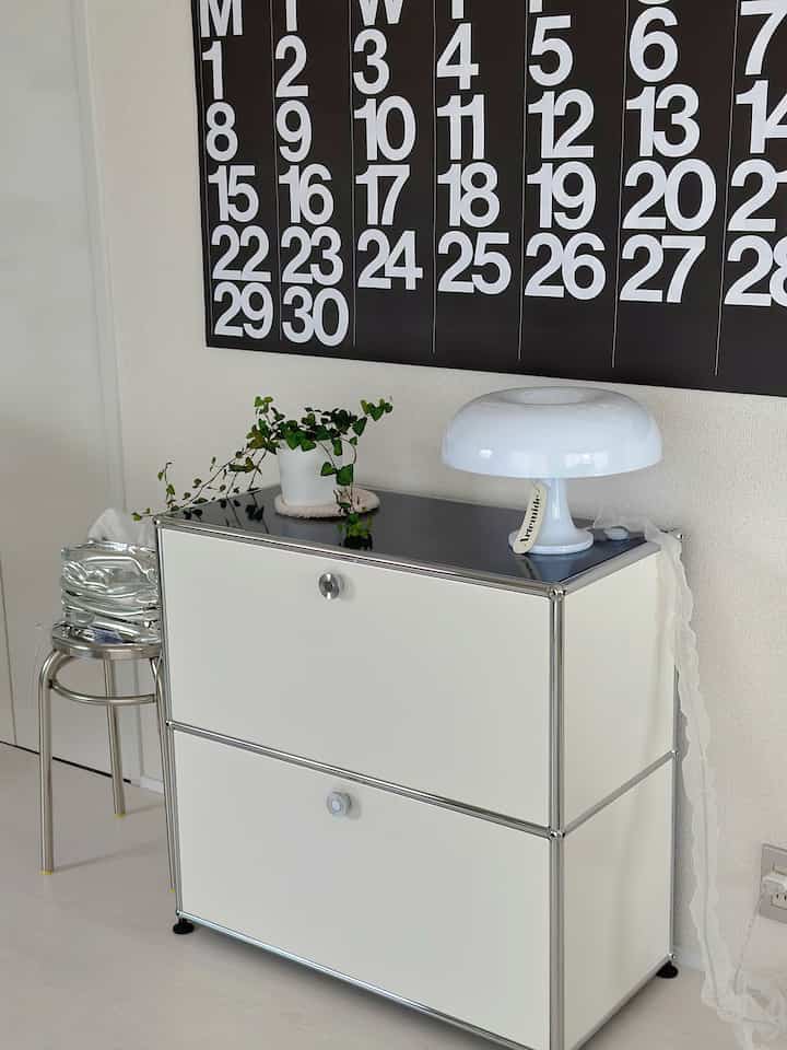 Modern space in white and silver tones featuring a sideboard and stool with clean, minimalist decor