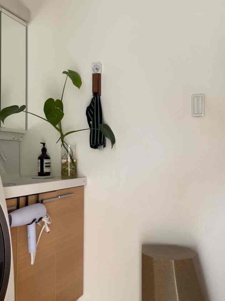 白い壁と木目調キャビネット、スツールが配置されたシンプルな洗面所の空間