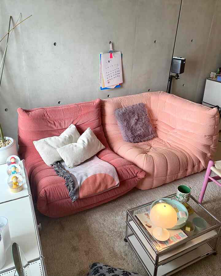 ピンク調のリビングルーム、L字型ソファとテーブルランプが配置された雰囲気のあるインテリア