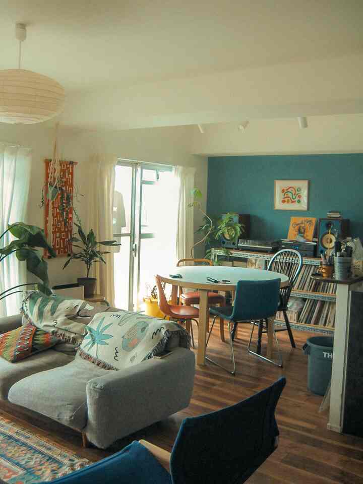 Bright white and blue toned living room featuring plants, sofa and dining table with warm natural atmosphere
