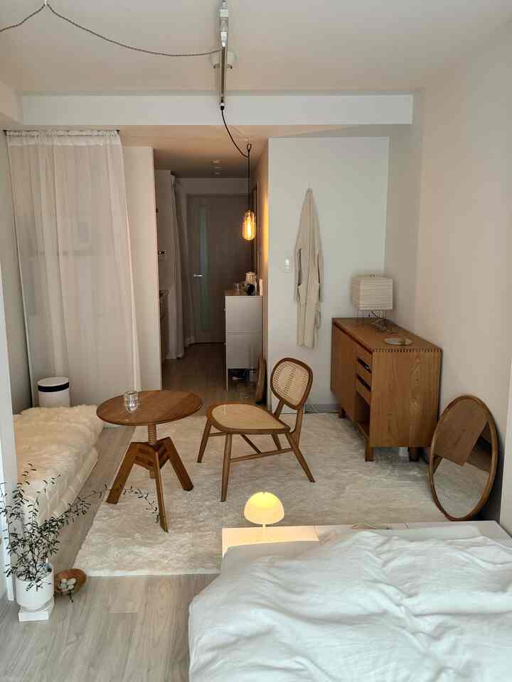 ナチュラルな色調のワンルーム寝室、木製家具と温かみのある照明が配置された印象的で穏やかなインテリア