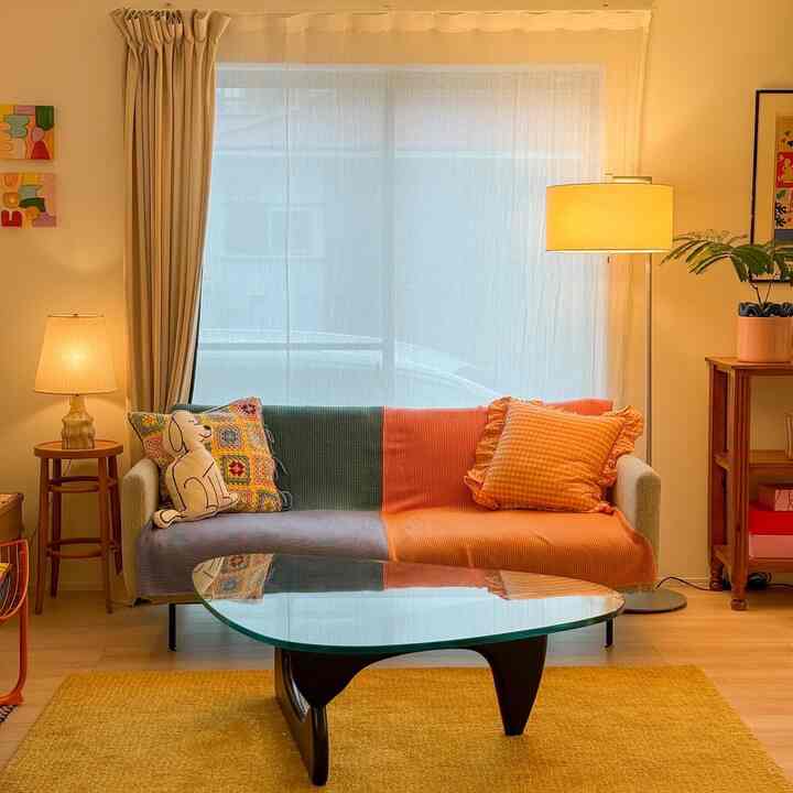 暖かいオレンジ色調のソファと照明が配置された雰囲気のあるリビングルーム