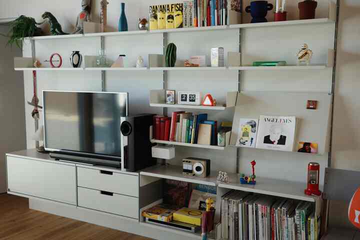 白を基調としたリビング、ミニマルなホワイトシェルフとテレビ台に本やインテリア雑貨が配された印象的な空間