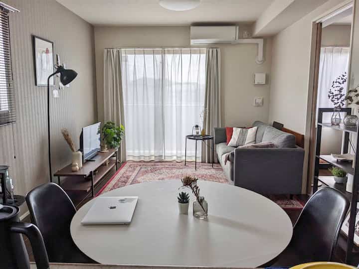 Bright white and beige toned spacious living room featuring a round table and gray sofa in a natural modern style