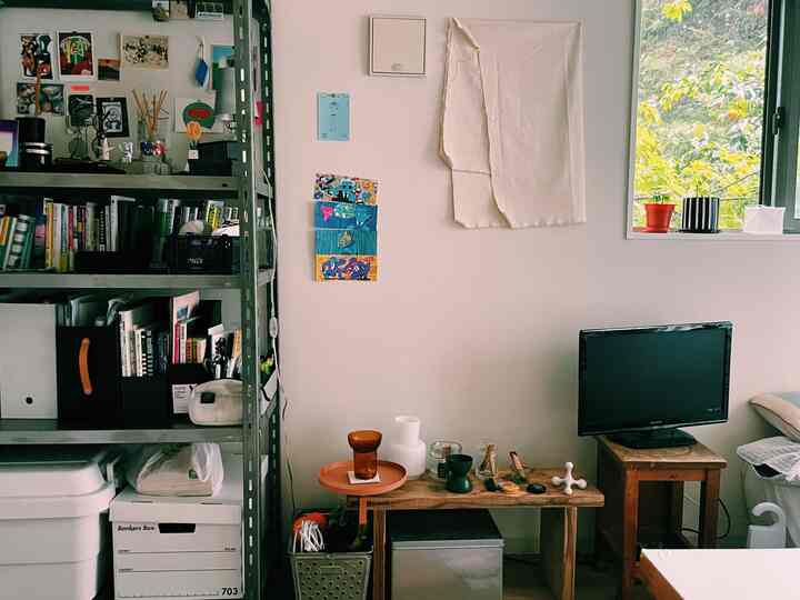 白い壁と茶色の家具が配置されたリビング、収納棚と小さなテーブルが調和する雰囲気のある空間