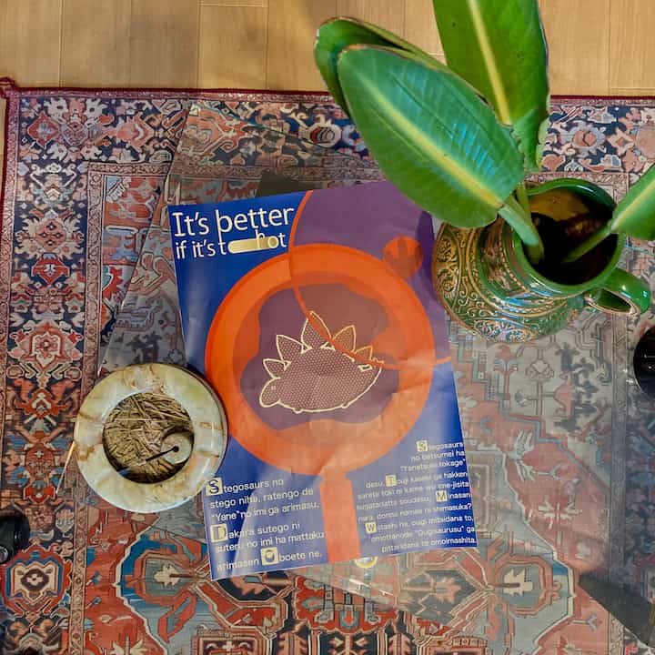 温かみのある赤と青のトーンのオリエンタルラグに覆われた空間、透明なガラステーブルとヴィンテージのオブジェが配置された雰囲気のあるインテリア