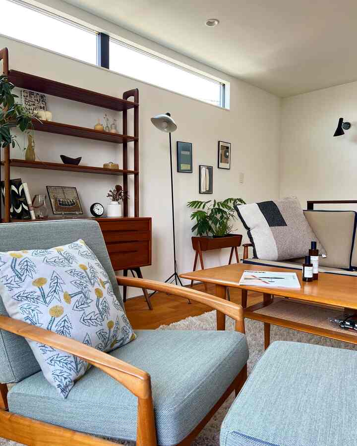 A Scandinavian-style two-person living room with white walls and wood tone furniture, featuring natural plants and cozy sofas