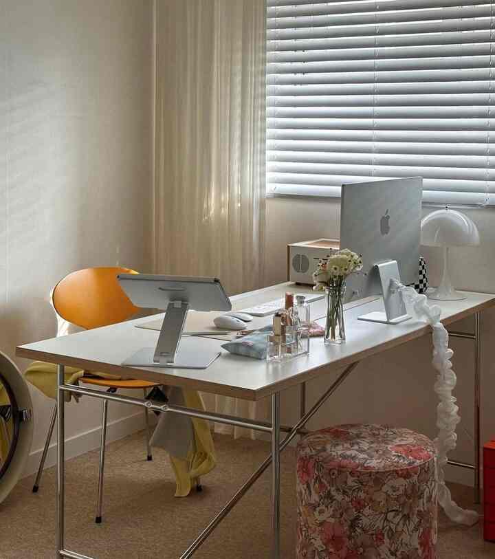 The orange chair and floral stool fill the space with charm. #ColorfulAccents #FloralTouches #InteriorDelight