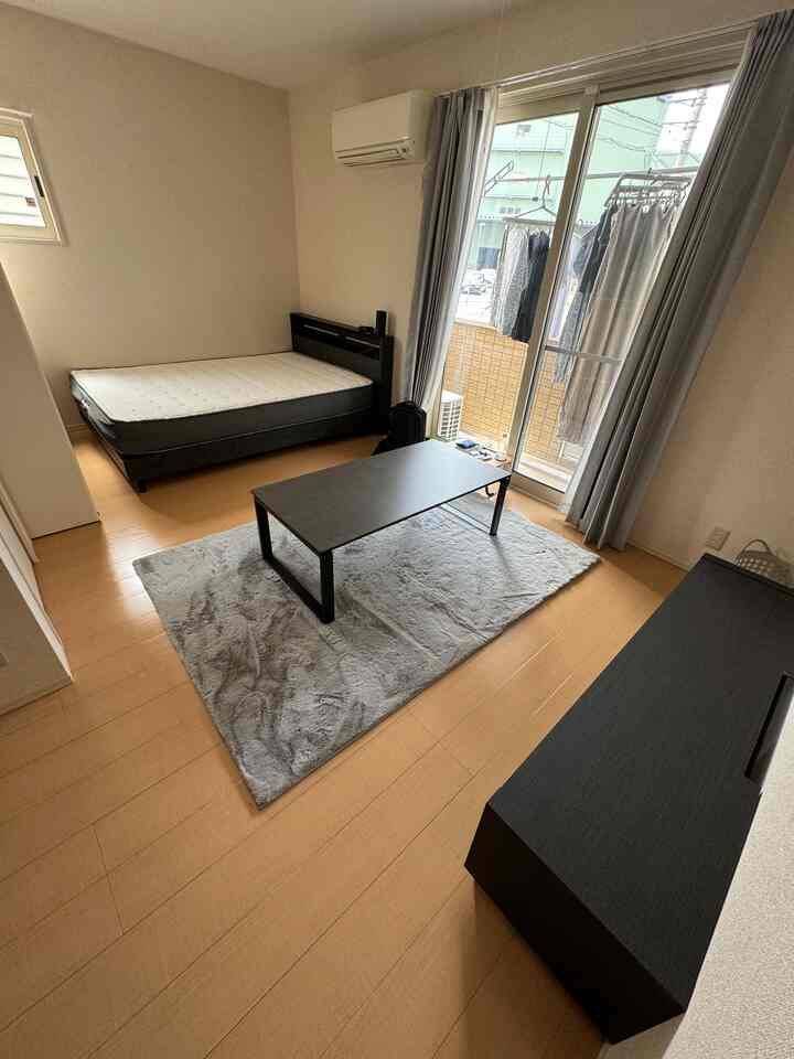 Natural tone studio bedroom featuring black furniture and a gray carpet creating a clean, minimalist space