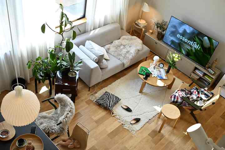 木目調と白を基調とした北欧風リビング、グレーのソファとアームチェア、デスク、植物が配置された雰囲気のあるインテリア