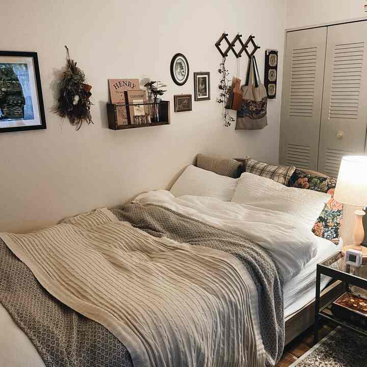 Calm beige and white toned bedroom featuring a bed, nightstand, and vintage-style decor elements