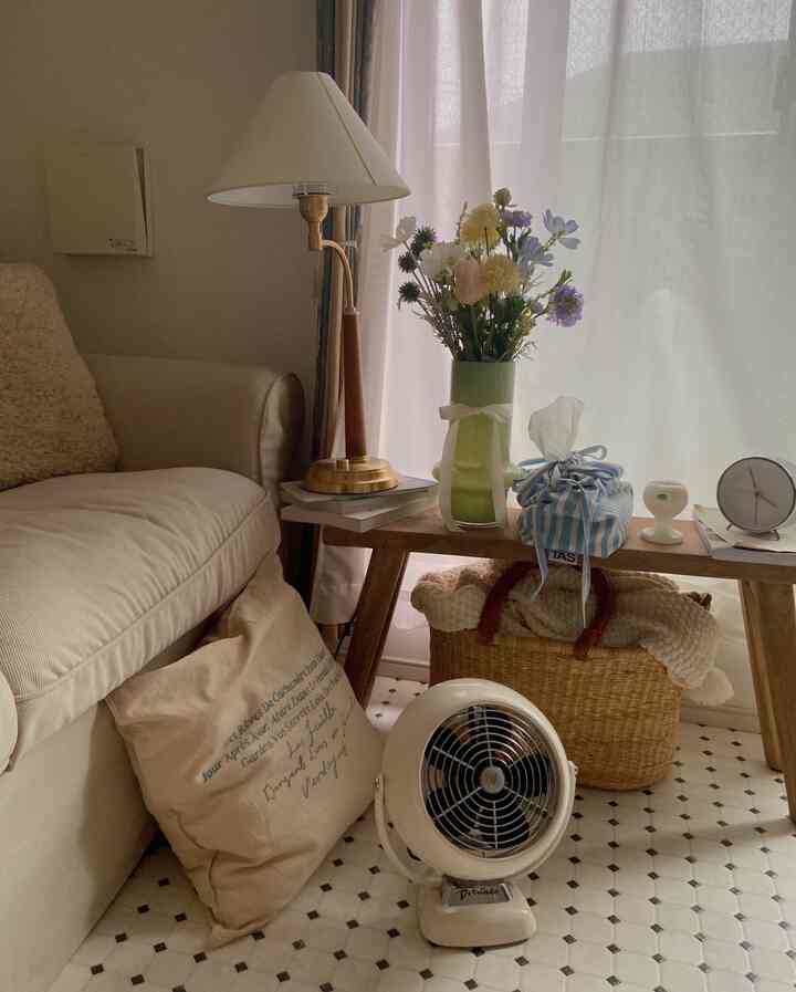 ナチュラルな色調のリビング、ベージュのソファと木製のベンチに花瓶や小物が配置された雰囲気のある空間