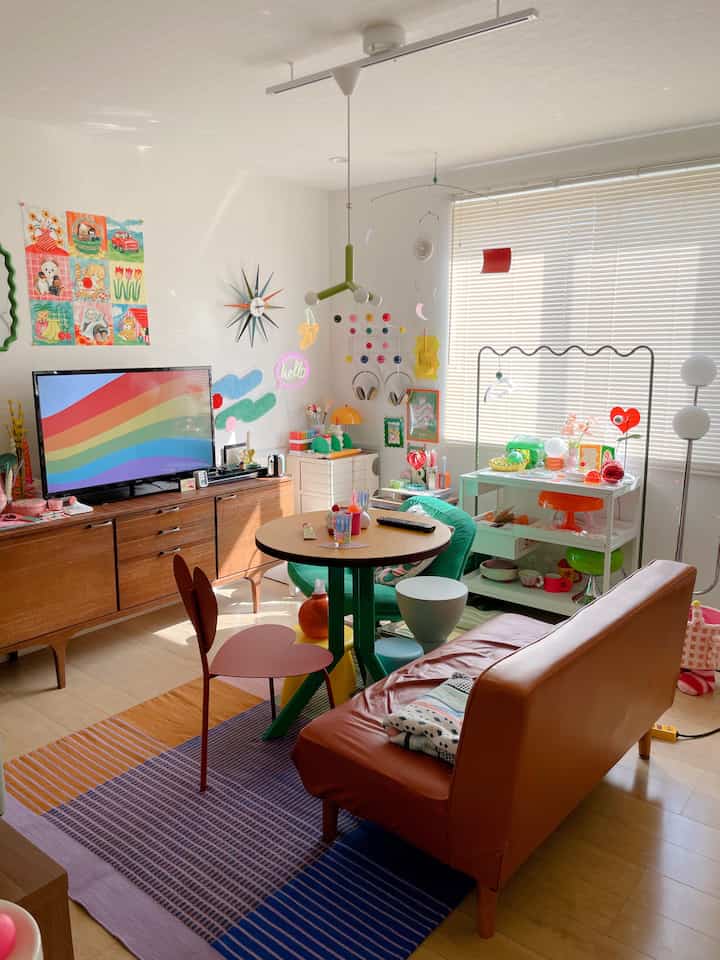 温かみのある色調とカラフルな小物が配置されたリビング、ブラウンのソファと丸テーブルが中心にある印象的な空間