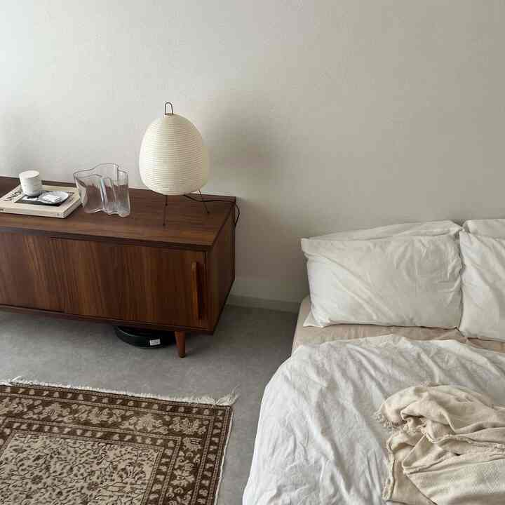 白と茶色のトーンのワンルーム寝室、シンプルでナチュラルな家具と寝具が配置された印象的な空間